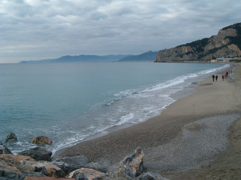 una spiaggia di sabbia e il mare, vista dall'alto della scogliera rocciosa