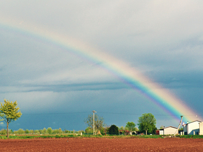 campo arato e casolare di campagna, nel cielo l'arcobaleno