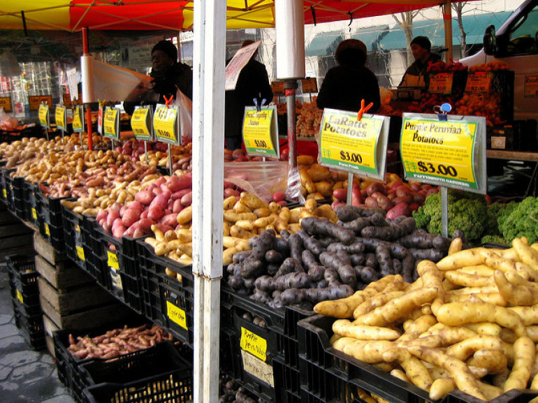 casse di patate e altri ortaggi sui banchi di un mercato