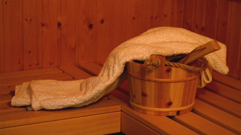 in sauna: secchiello con acqua e parete di legno