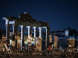 Ciclisti si riposano davanti ai Fori Imperiali romani di sera
