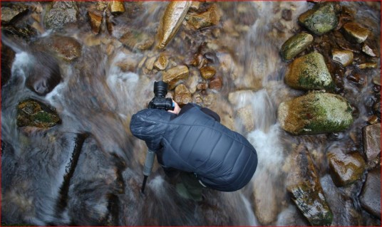 Un fotografo in mezzo a un torrente