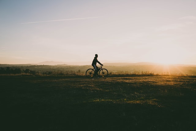 Uomo in bici nella natura con tramonto