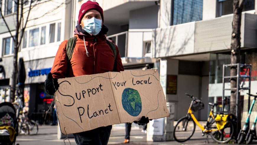 Uomo con cartello "supporta il tuo pianeta" per sensibilizzare il Countries Overshoot Day