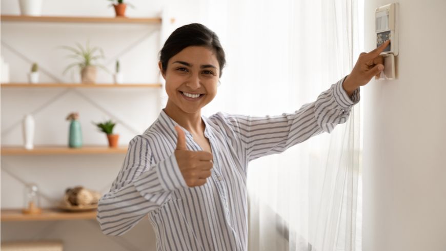 Woman adjusting her thermostat to avoid polluting with gas emissions