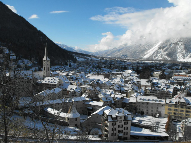 la città vista dall'alto con i tetti bianchi di neve e le montagne tutt'attorno