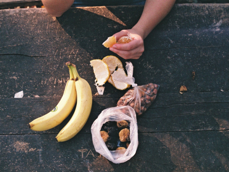 un tavolo di legno con appoggiata una banana e della frutta secca