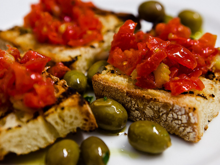 fette di pane condite con pomodori olio e olive fresche