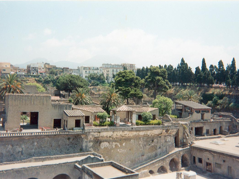 I resti della città antica di Ercolano con dietro quella moderna. Sullo sfondo il Vesuvio.