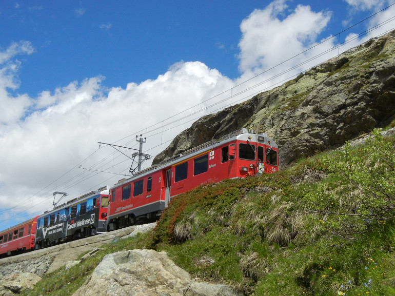 treno rosso che attraversa un passo alpino