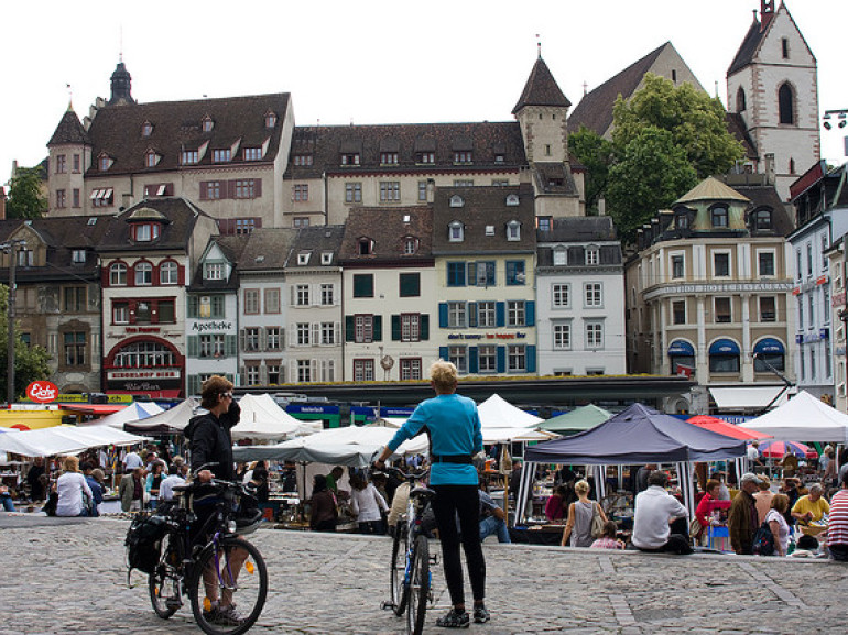 due ciclisti in una piazza con bancarelle del mercato