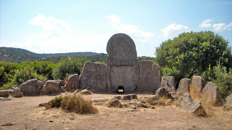 Monumenti in pietra lavorata. Grandi lastre una vicino all'altra formano un cortile attorno all'ingresso della tomba