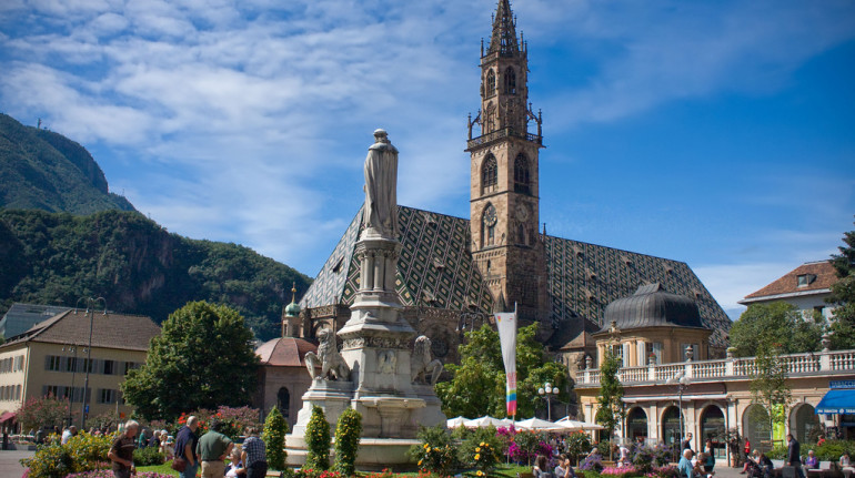 la piazza del duomo di bolzano. tipica la chiesa con il tetto verde e le sue guglie e la grande fontana fiorita al centro della piazza