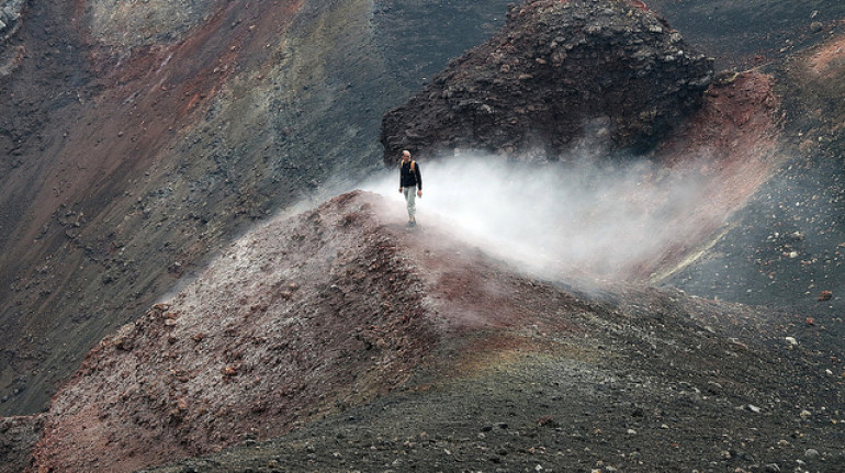 le nere pendici del vulcano etna e una persona che le attraversa a piedi